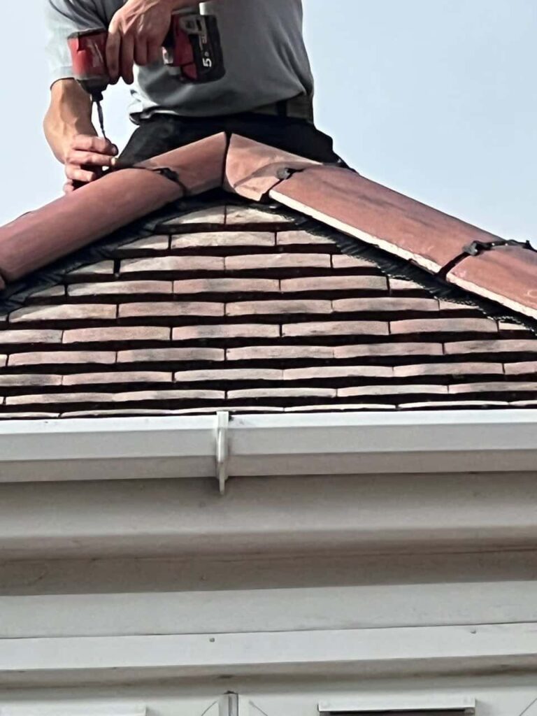 This is a photo of one of the operatives of Burntwood Roofing Repairs installing new ridge tiles